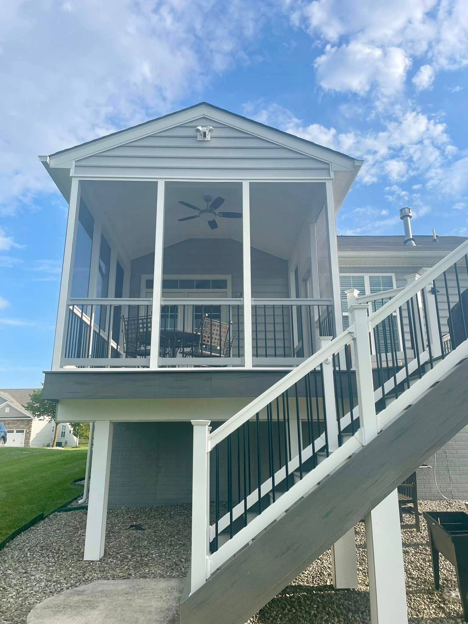 A house with a screened in porch and stairs leading up to it.