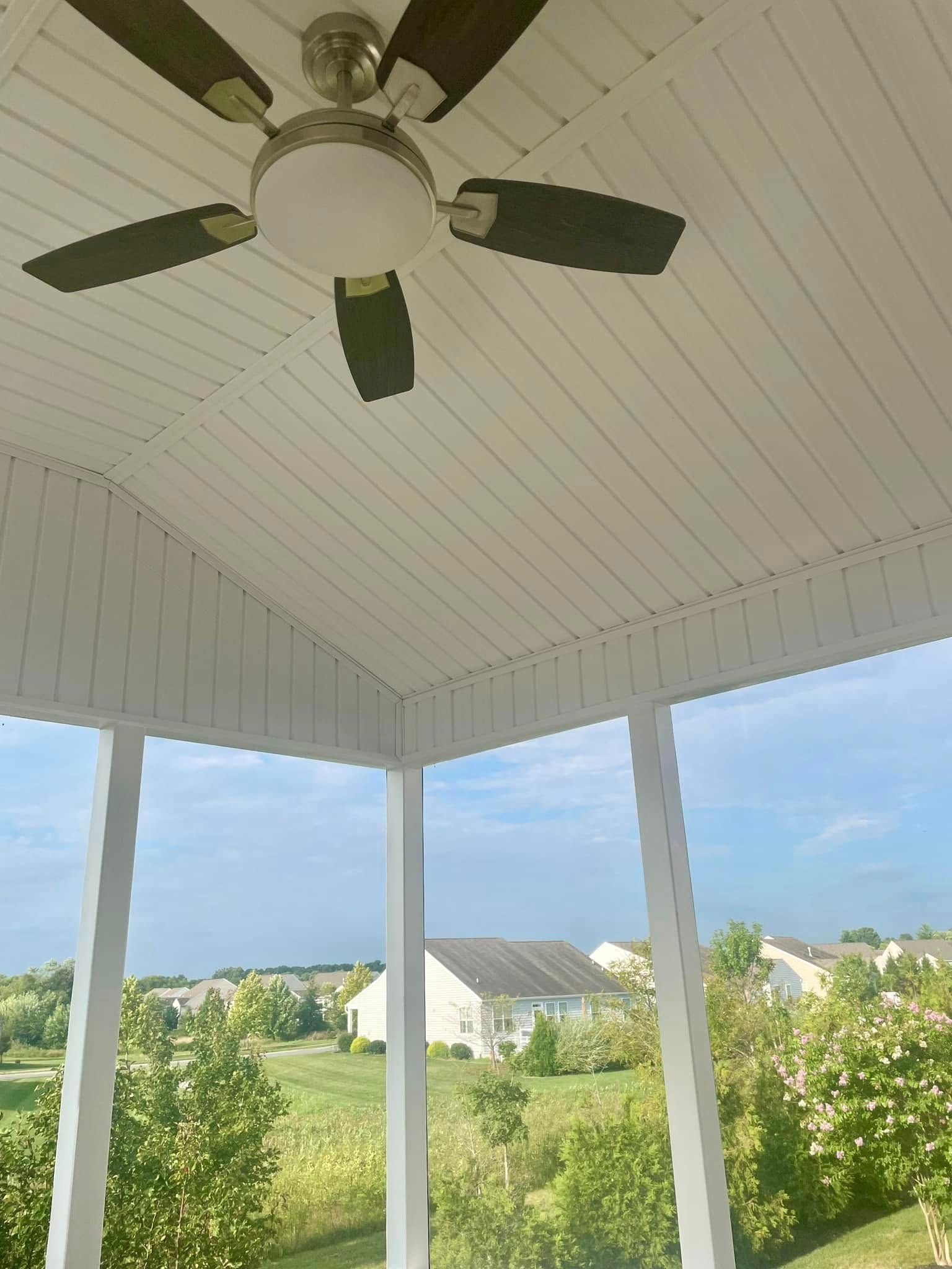A ceiling fan is hanging from the ceiling of a porch