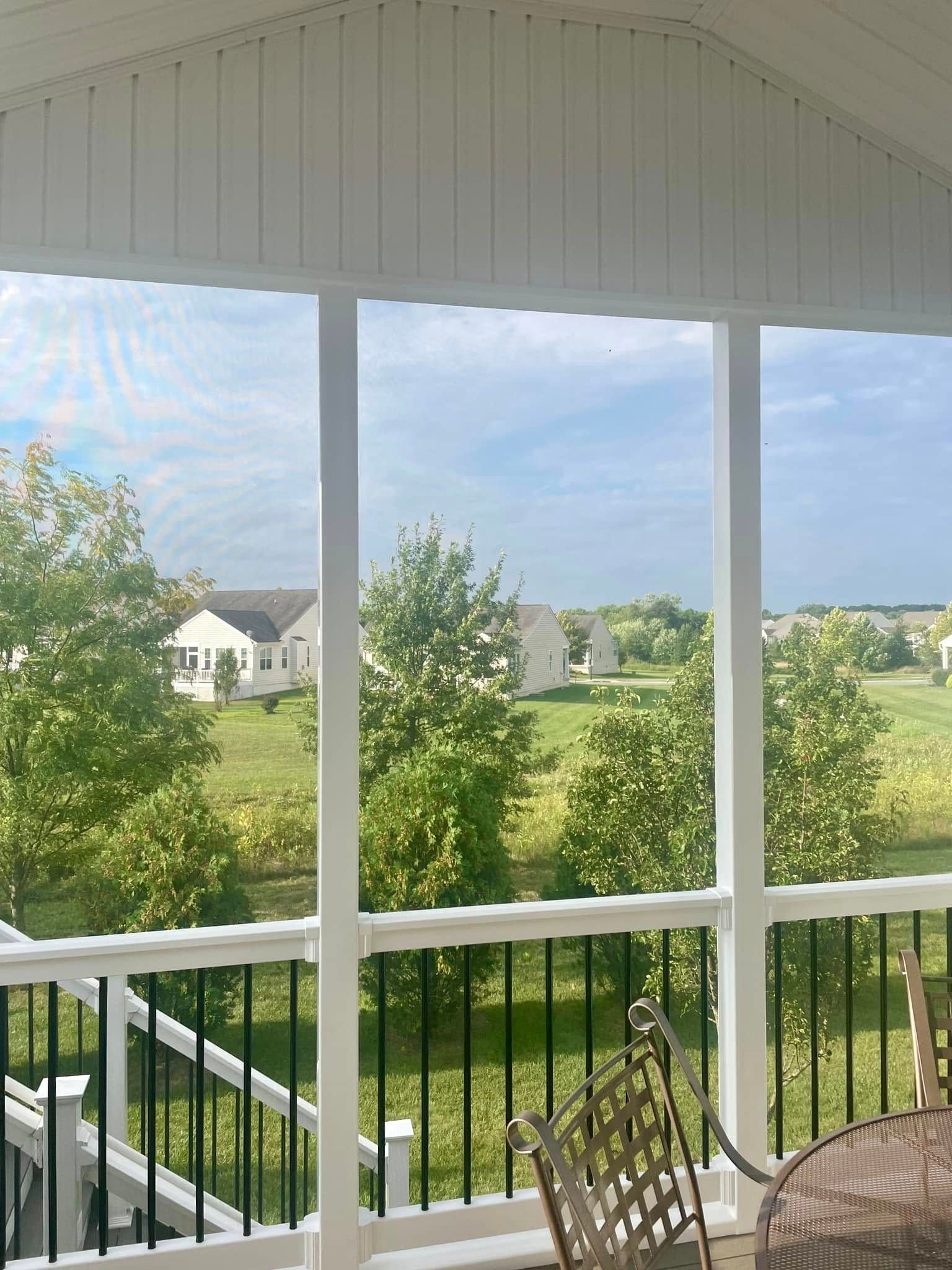 A porch with a table and chairs and a view of a field.
