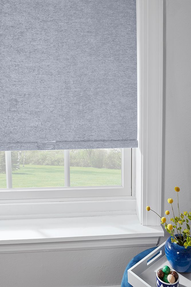 A window with a blue blind and a vase of flowers on the window sill.