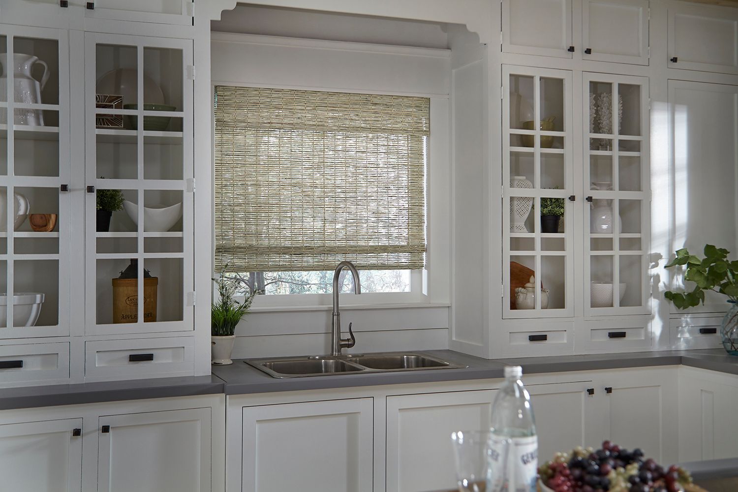 A kitchen with white cabinets , a sink , and a window.