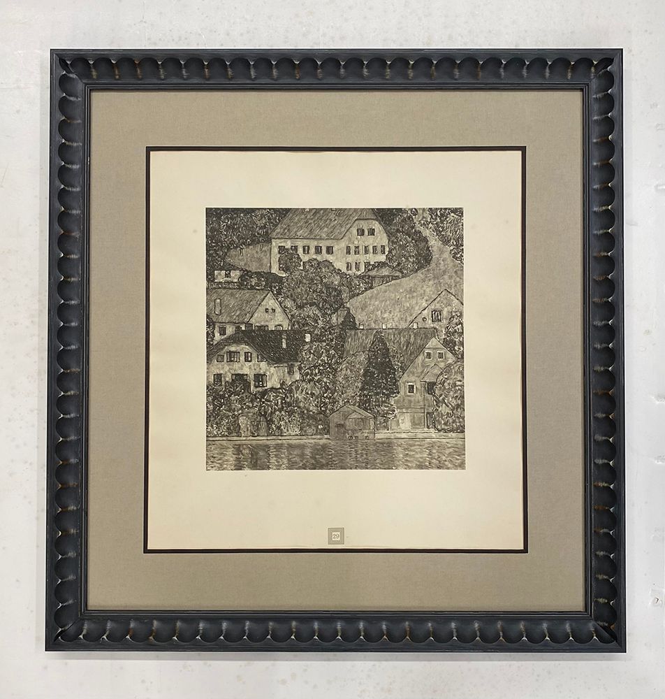 A framed picture of a landscape with houses and trees