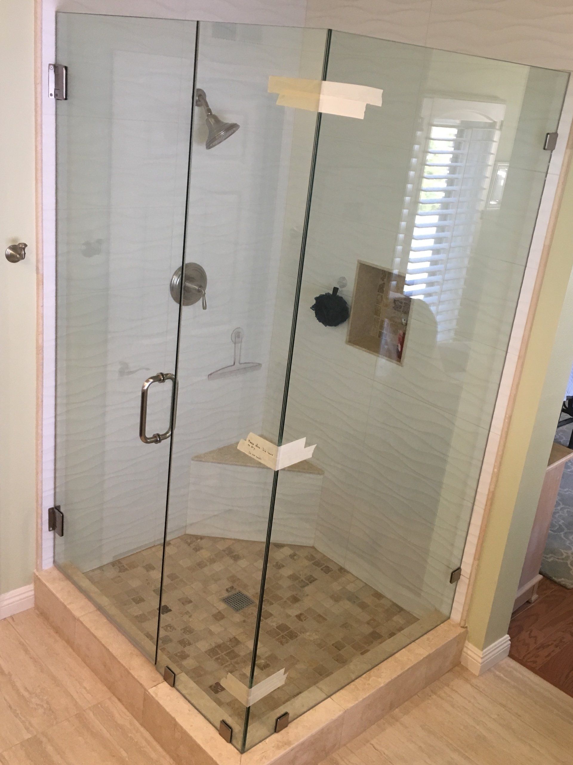A shower stall with a glass door and a shower head