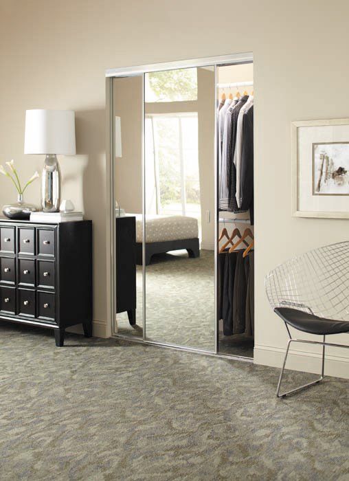 A bedroom with a dresser and chair and a walk in closet