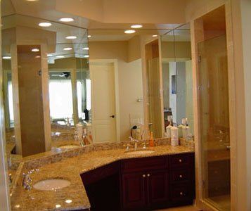 A bathroom with a sink , mirror and walk in shower.