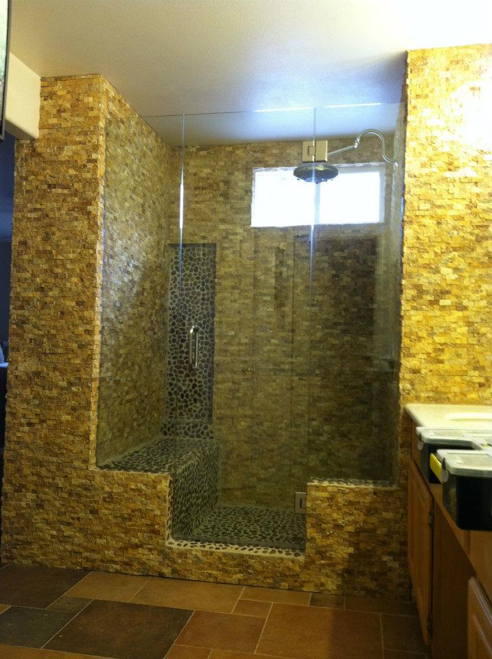 A bathroom with a walk in shower and a brick wall.