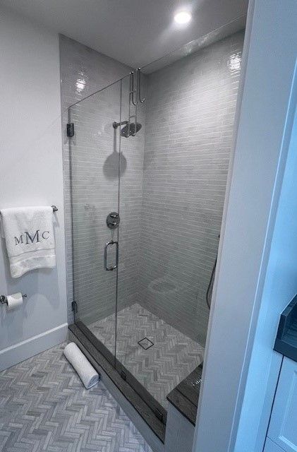 A bathroom with a walk in shower with a glass door.