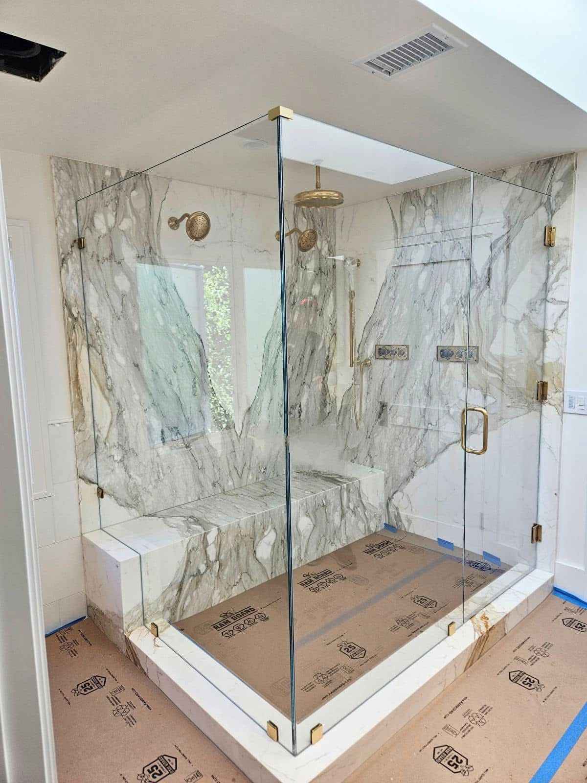 A bathroom with a walk in shower and marble walls.