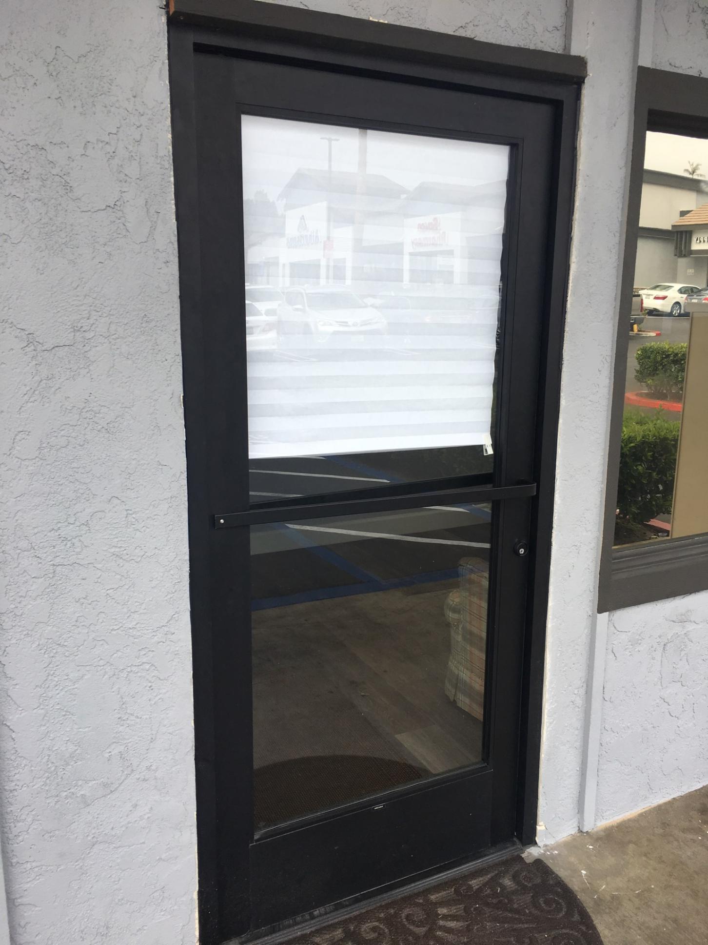 A black door with a clear glass window is on the side of a building.
