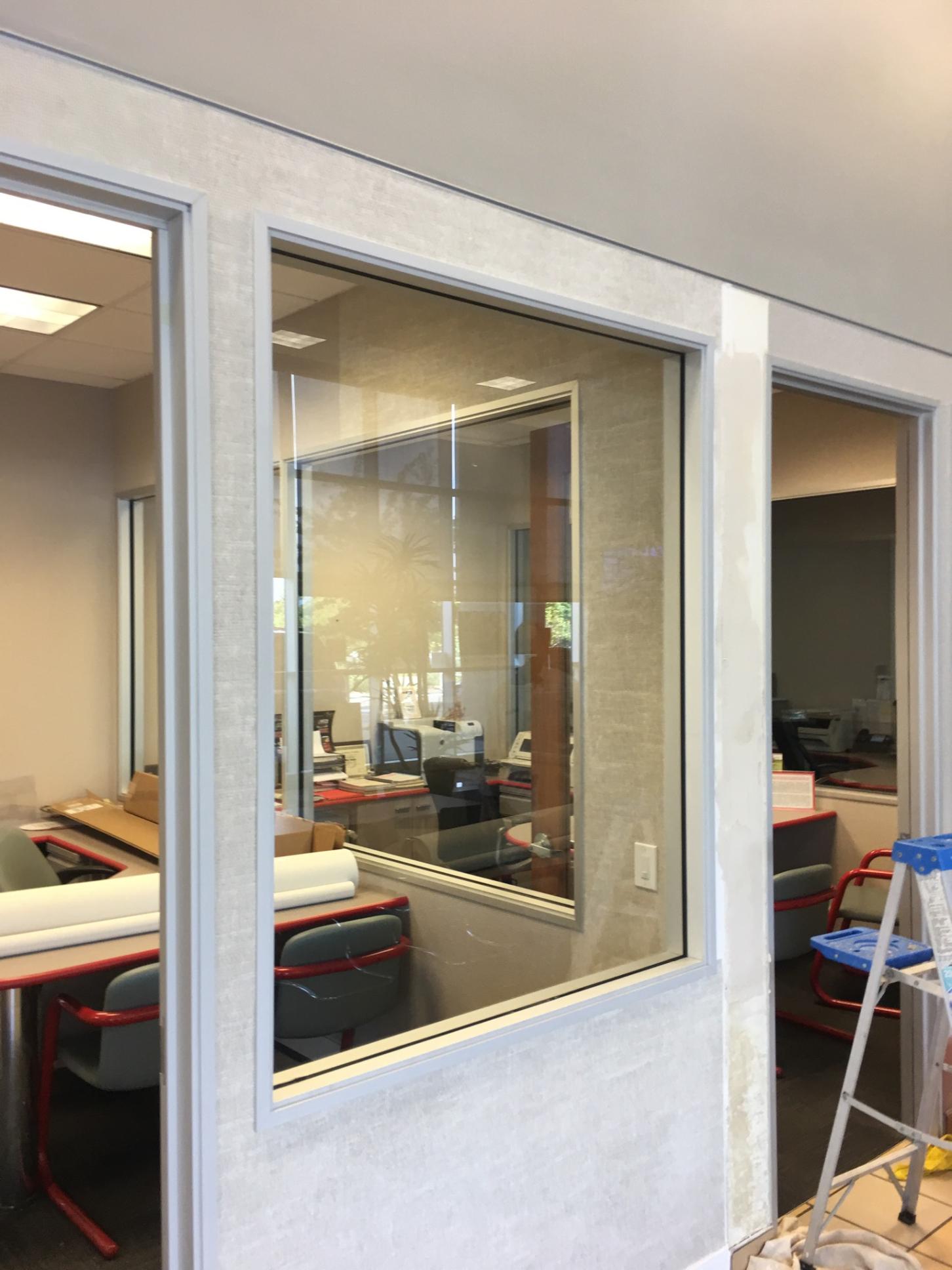 A ladder is sitting in front of a window in an office.