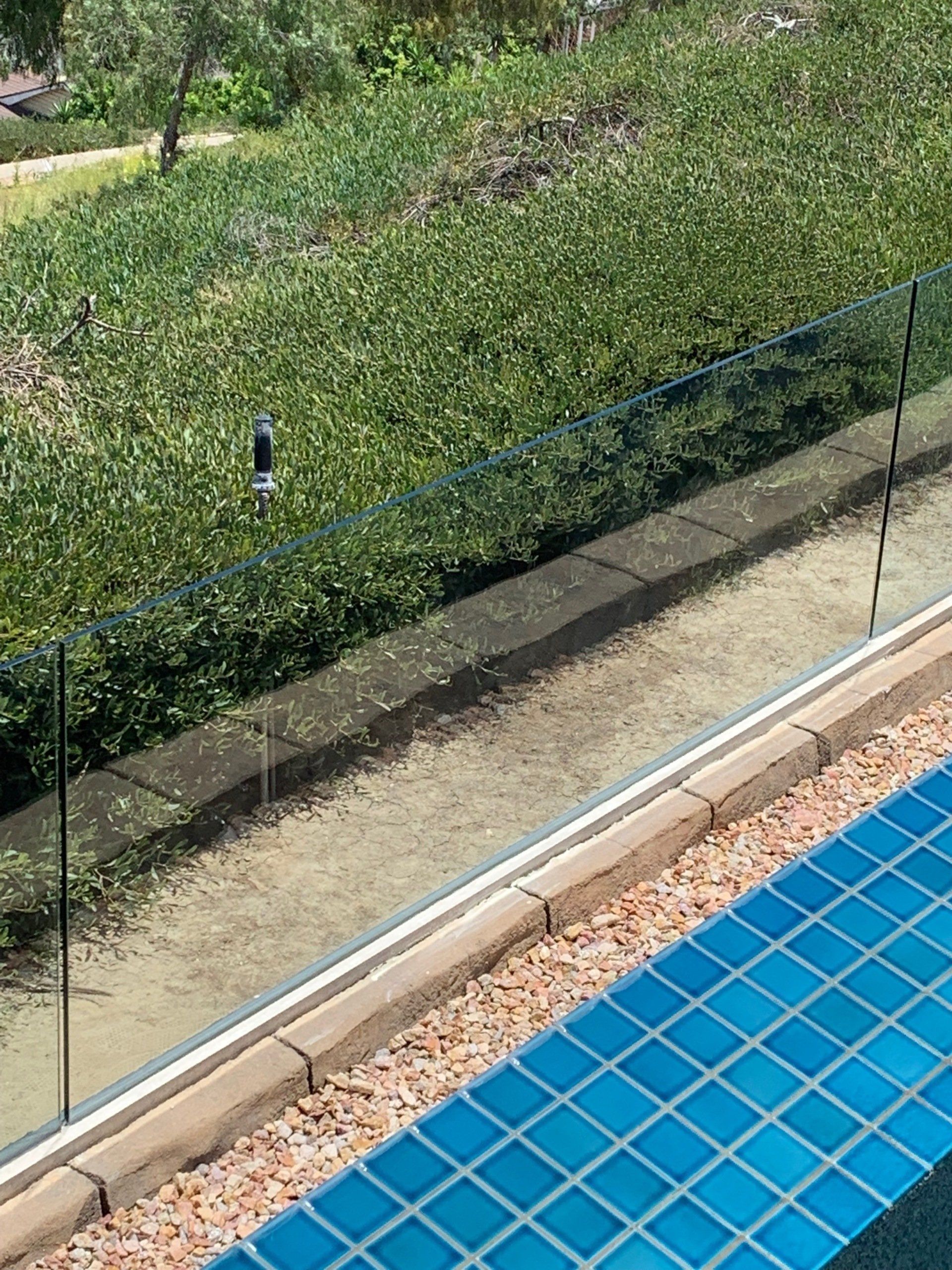 A swimming pool with a glass fence and blue tiles surrounding it.