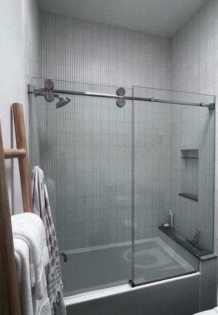 A bathroom with a sliding glass shower door and a bathtub.