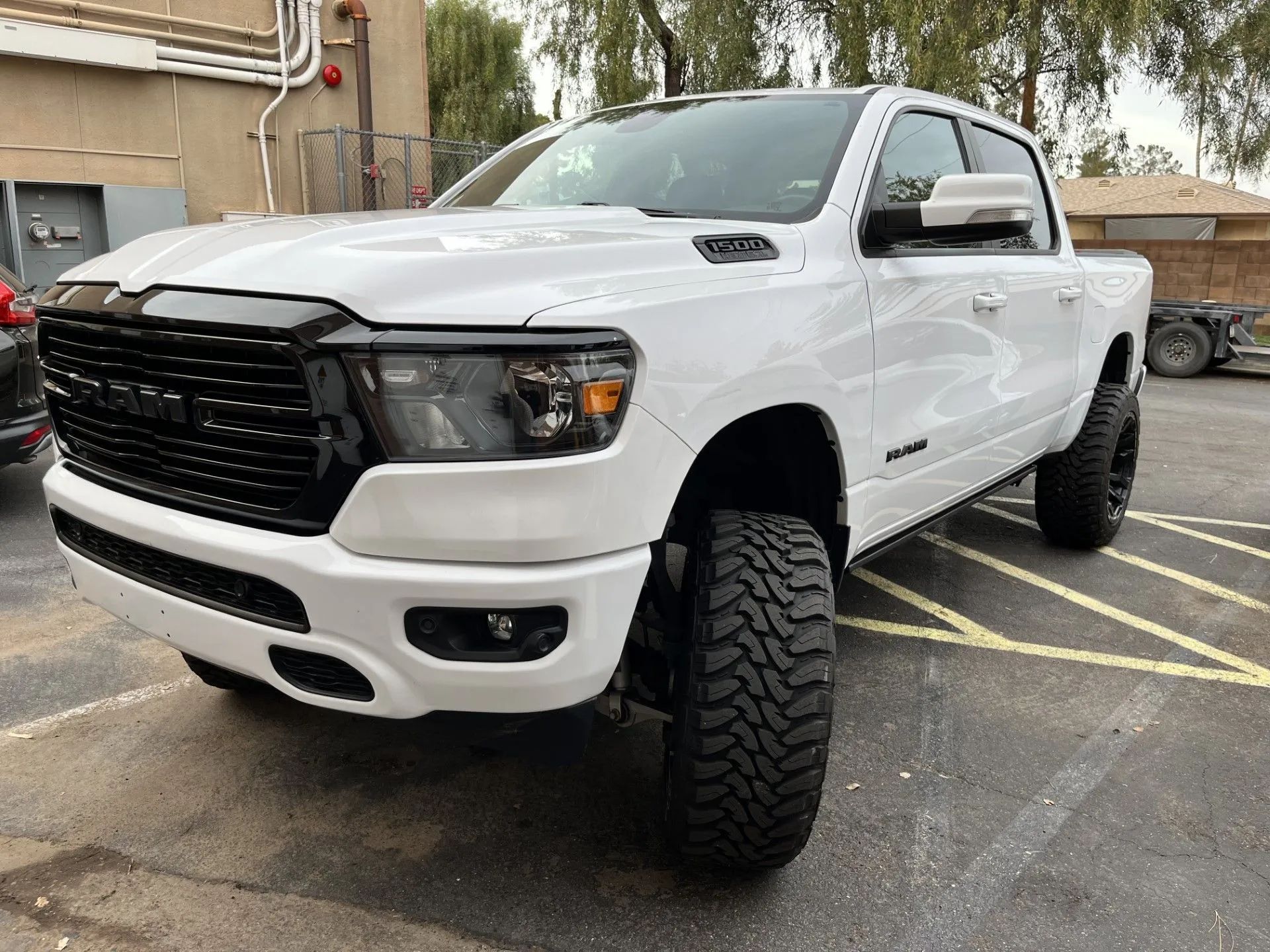 White Ram pickup truck with black grill, wheels, and tinted headlights parked outside.