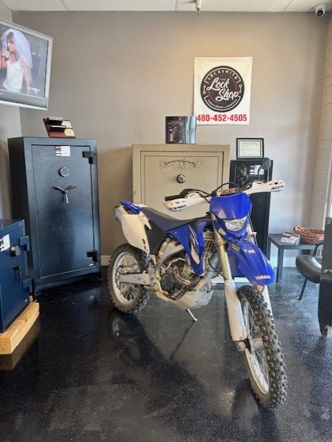 A blue and white dirt bike in a room with safes, a television showing a wedding photo, and a sign.
