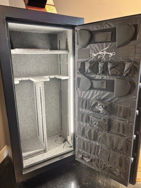 Open black gun safe with interior storage and door organizer.