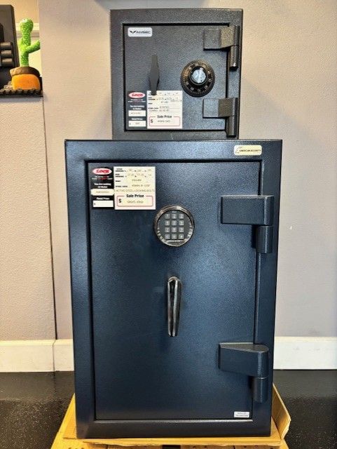 Two dark blue safes, one on top of the other. The bottom safe is larger, with a keypad. The top safe has a dial.