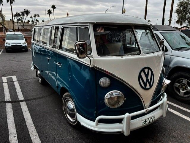 Blue and white vintage Volkswagen bus parked, cloudy day.