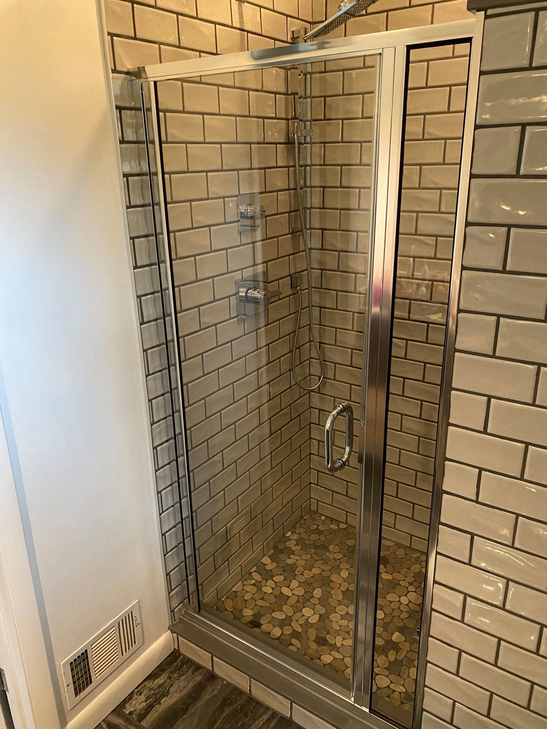 Shower door closed with pebble tile floor