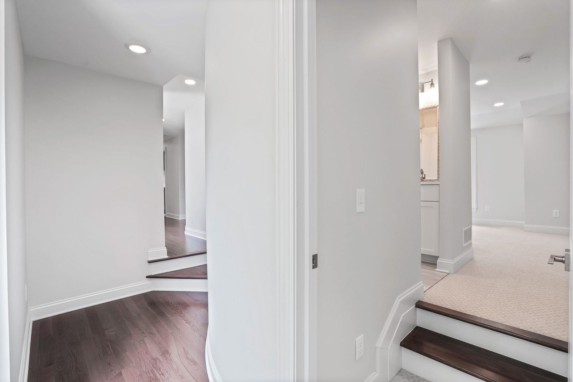 Hallway with dark wood floors, white walls, and stairs leading to other rooms.