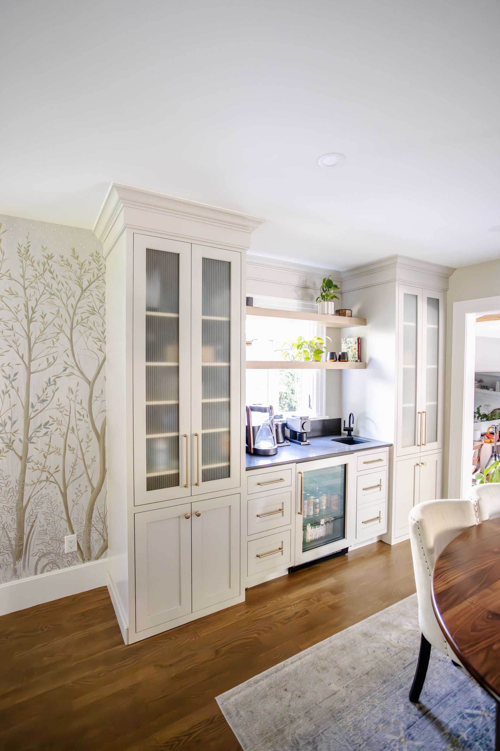 White built-in kitchen cabinetry with a beverage center, shelves, and a mini-fridge in a dining room.