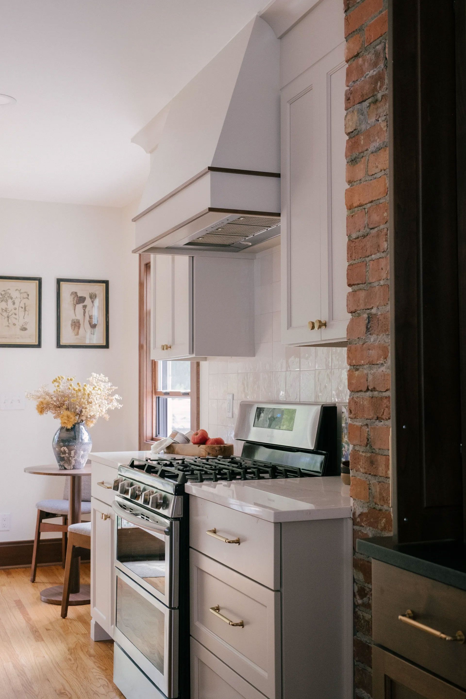 Kitchen with white cabinets, exposed brick, and a stainless steel stove.