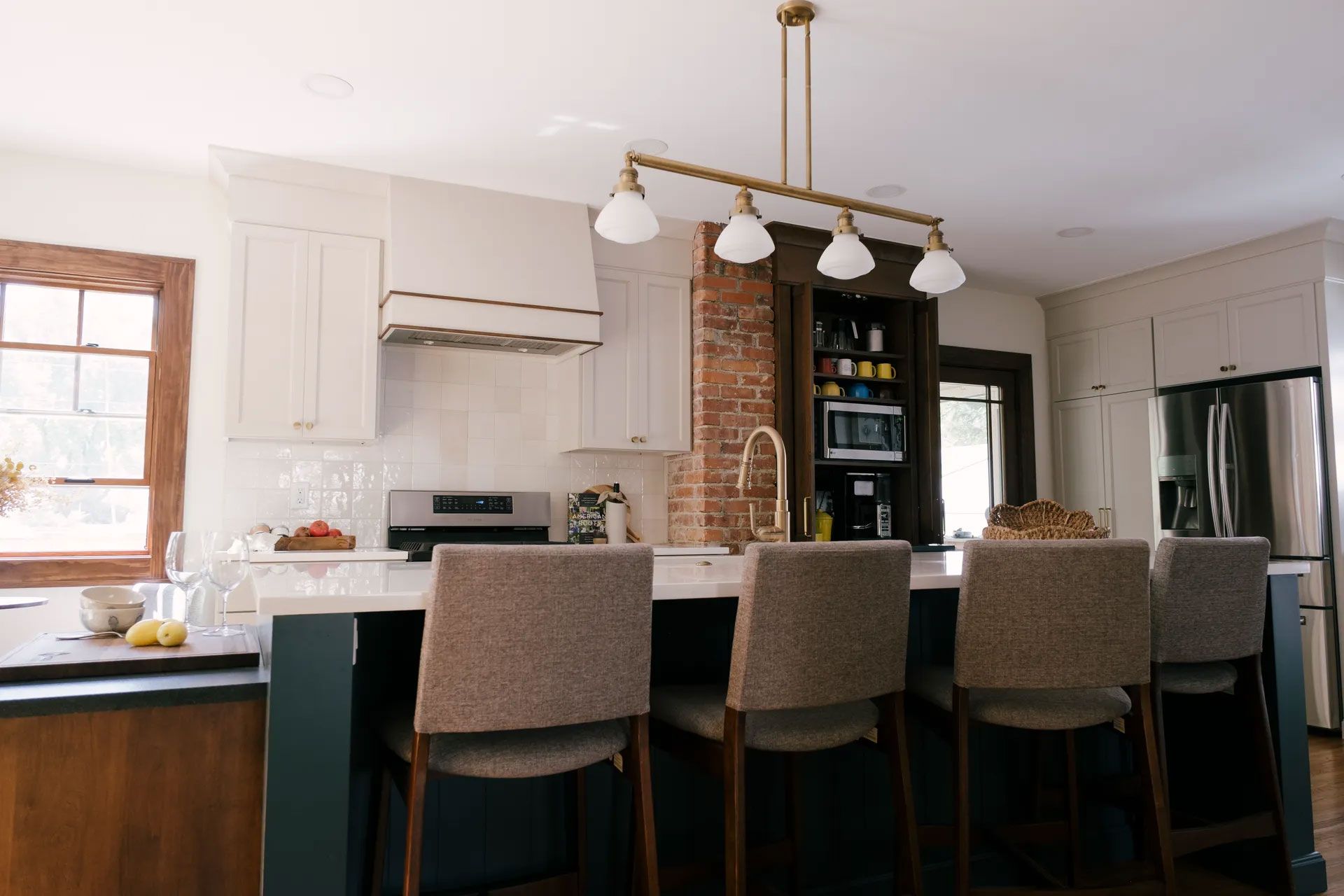Kitchen with dark blue island, white cabinets, and brass light fixture.