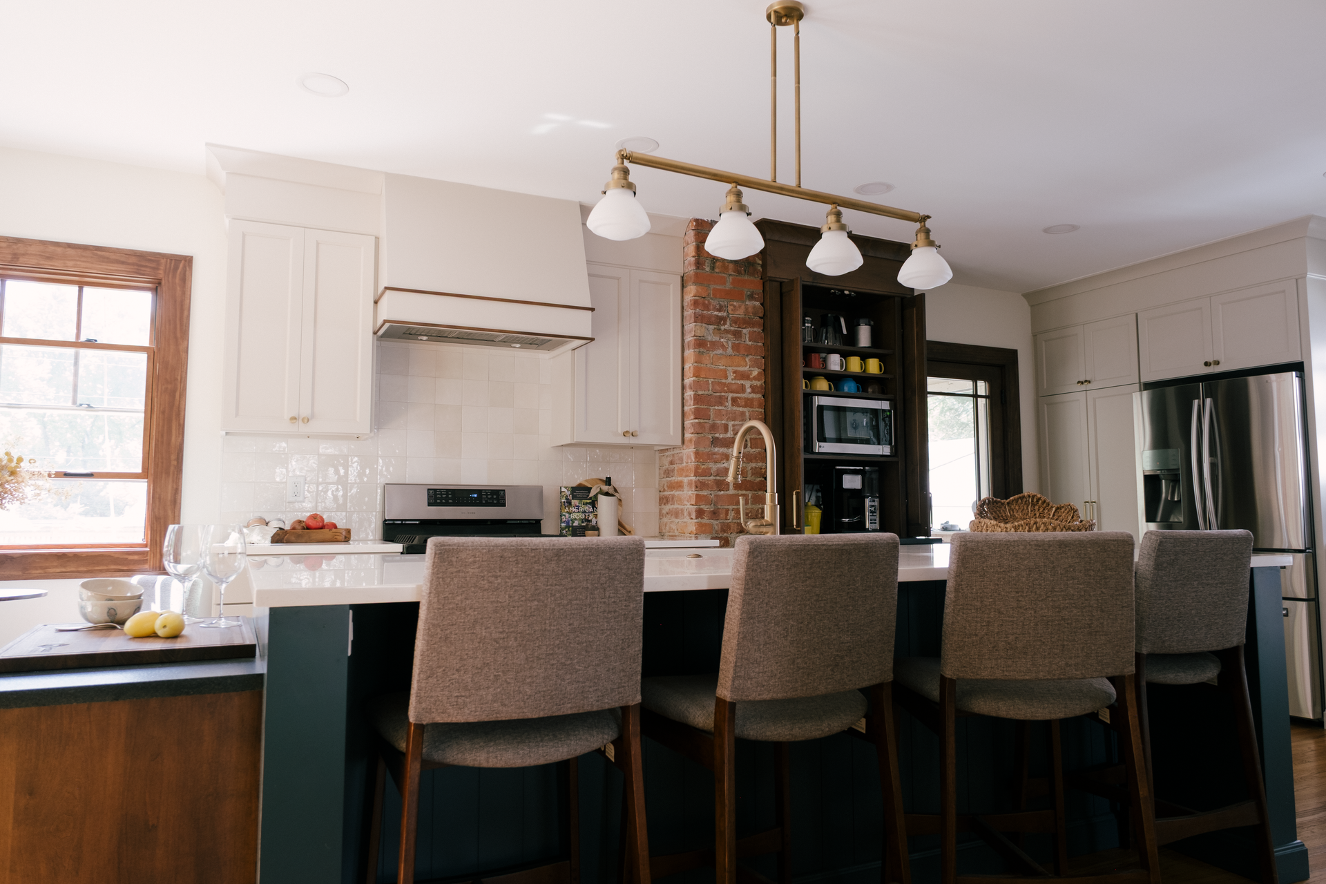 Kitchen with a dark green island, cream cabinets, and a decorative light fixture.