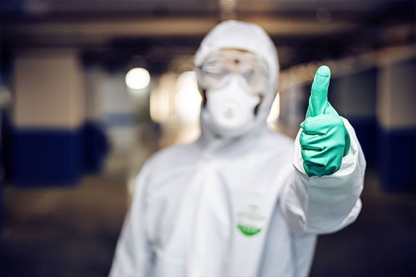 A man in a protective suit is giving a thumbs up.