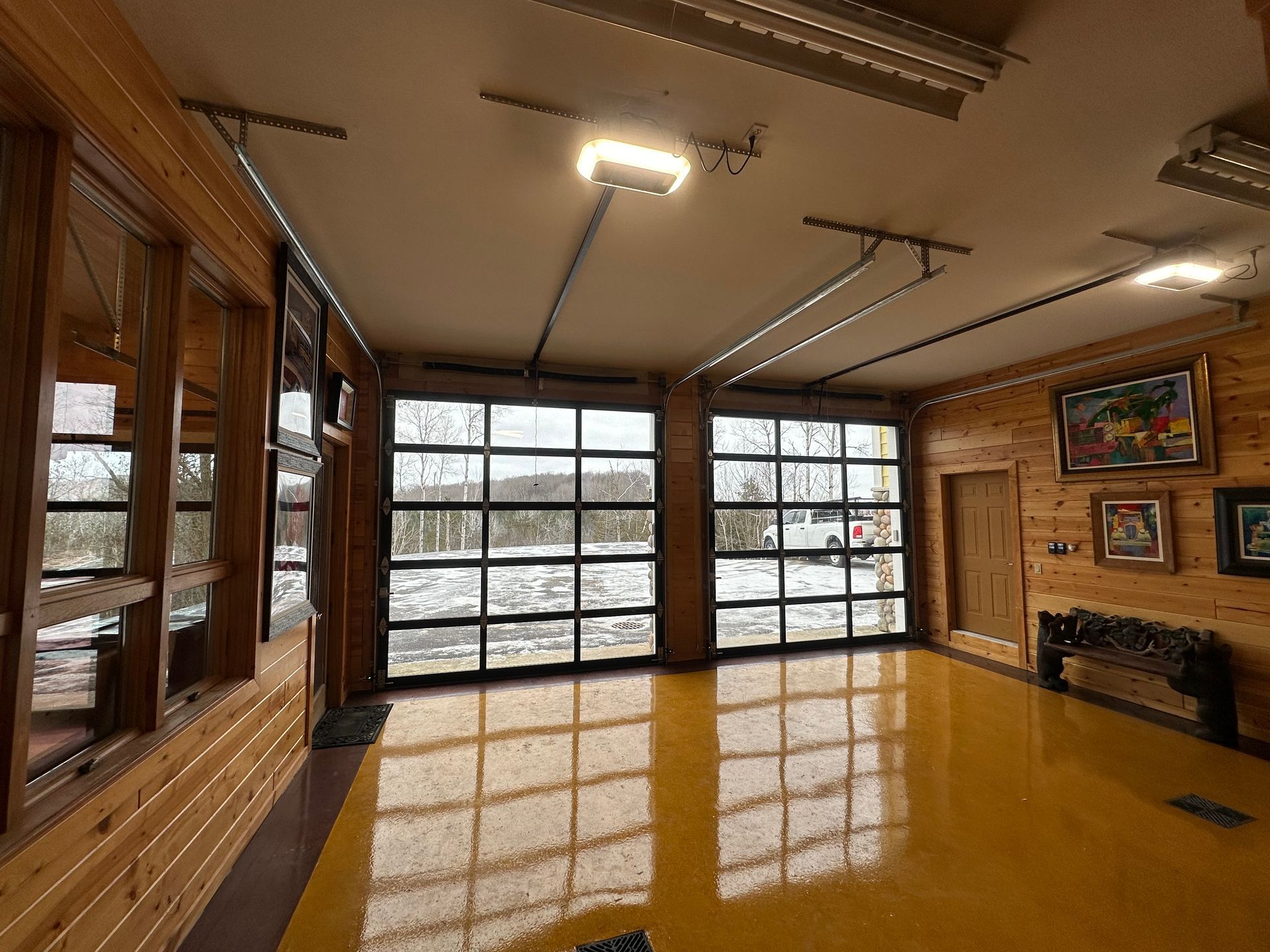 Garage interior with glass doors, yellow floor, and wooden walls. Outside is a snowy landscape.