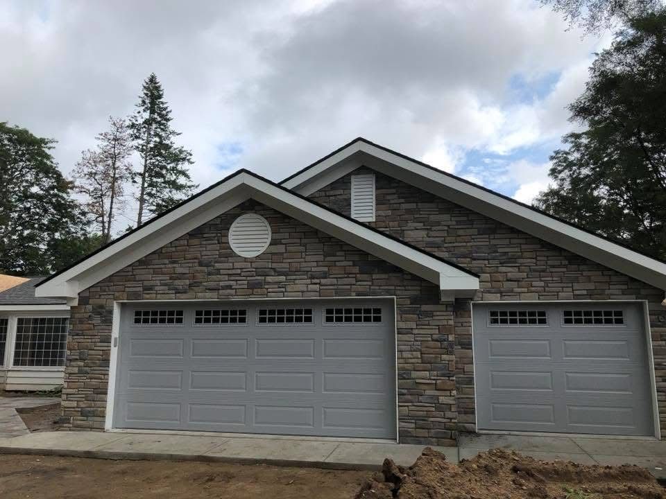 Stone facade garage with gray doors, under cloudy sky.