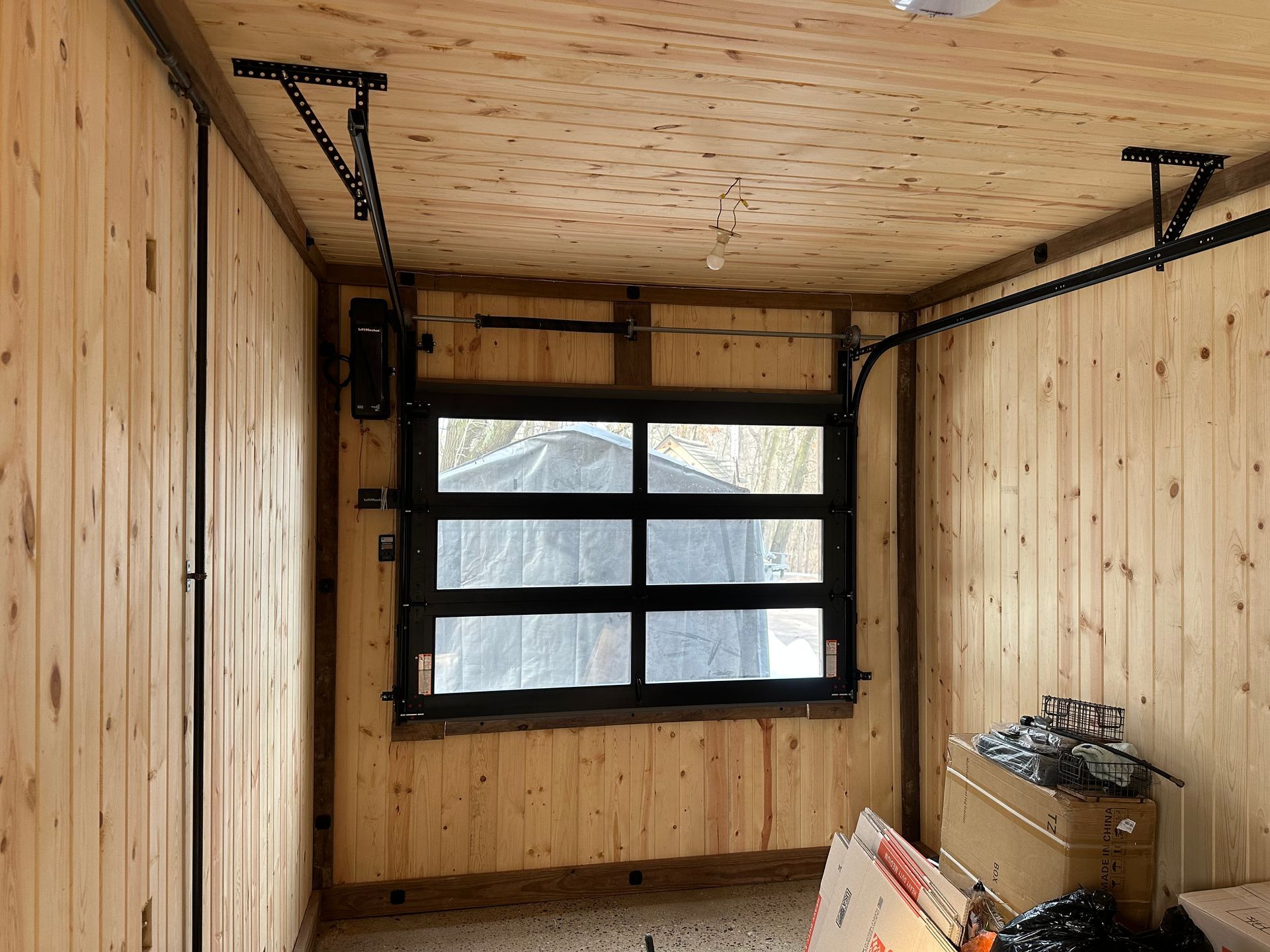 Interior of a wooden cabin with a black garage door and tracks.