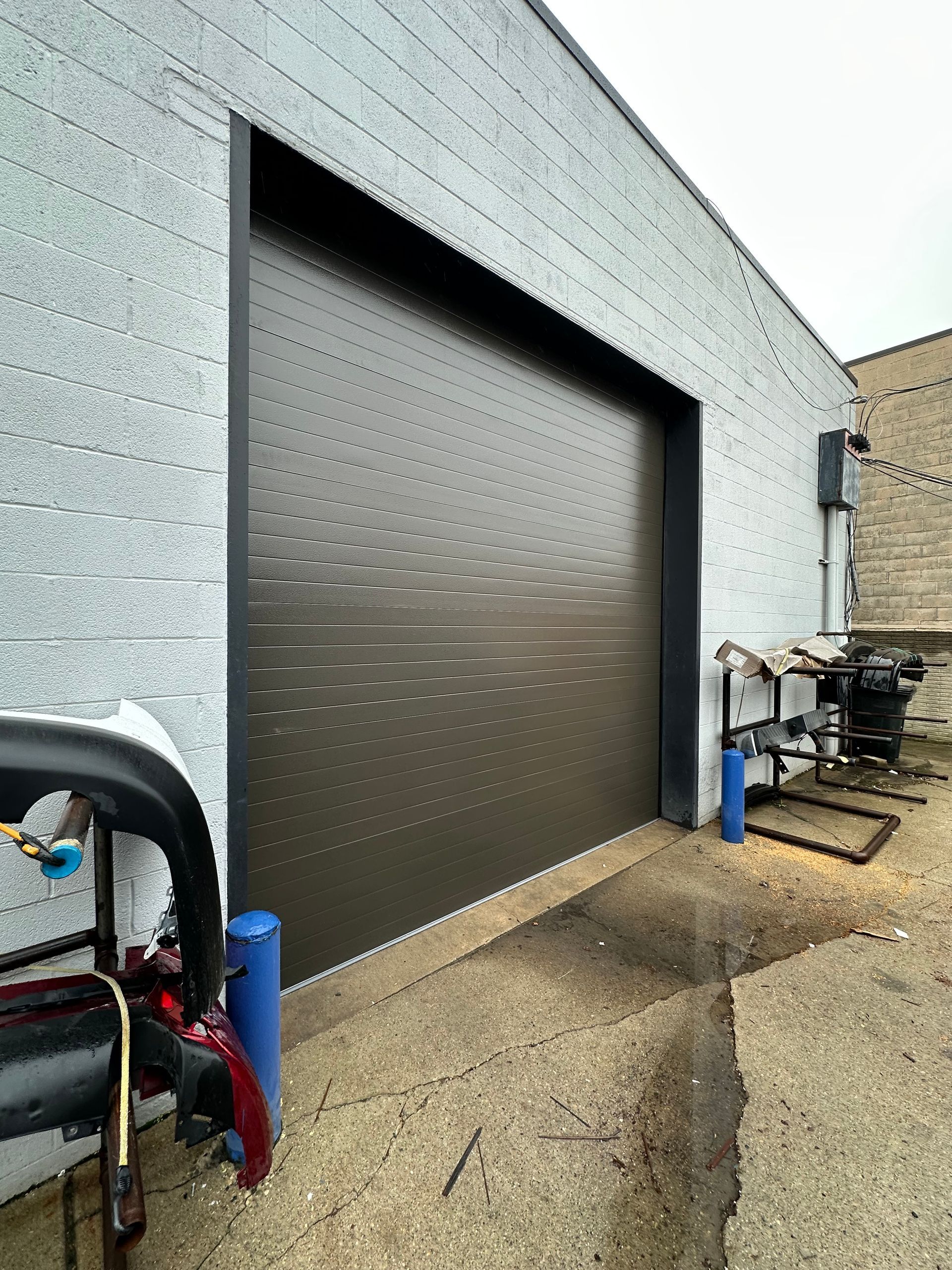 Dark gray garage door on a light gray brick building.