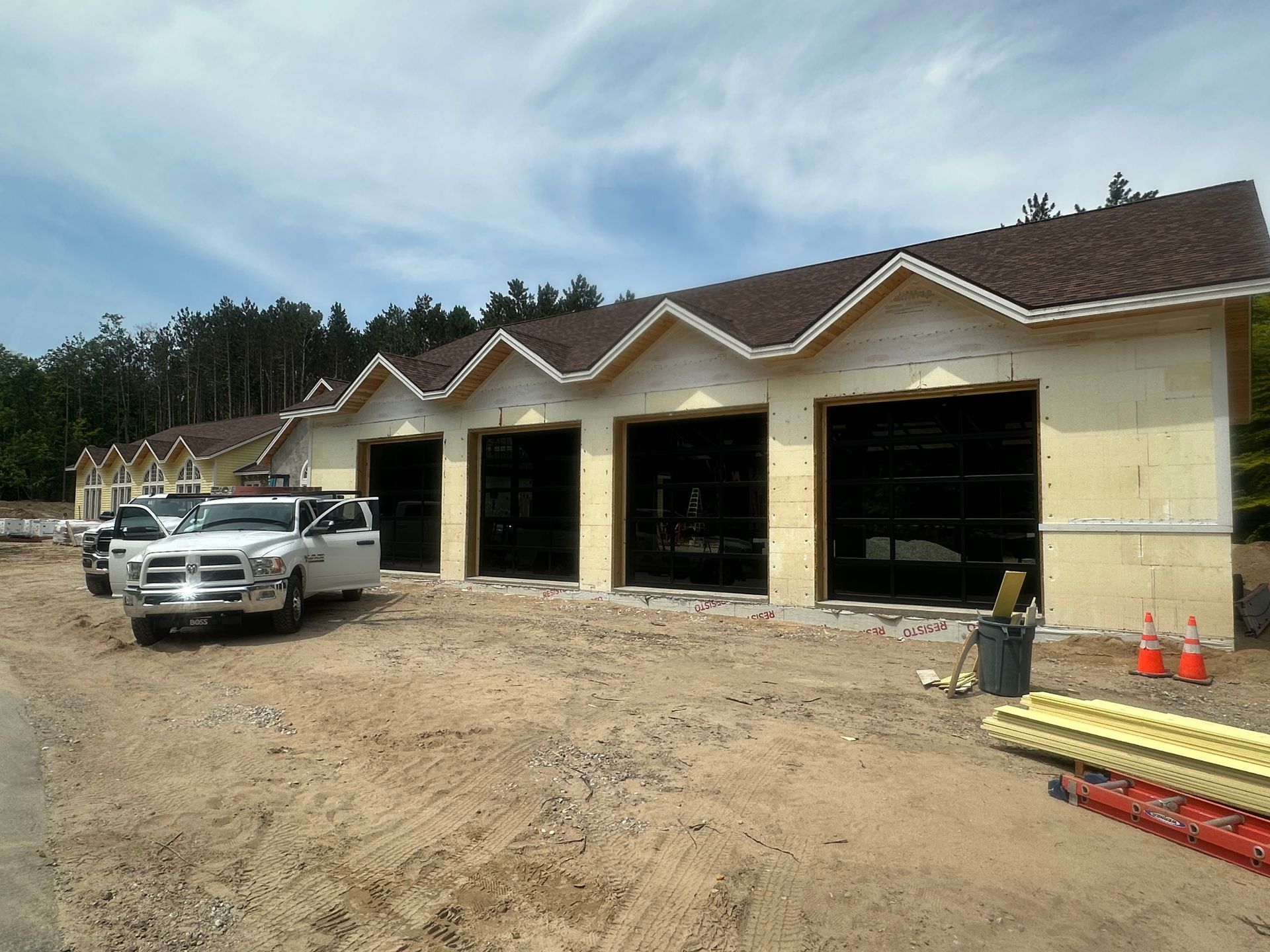 Construction site with garage bays, white truck, and supplies.