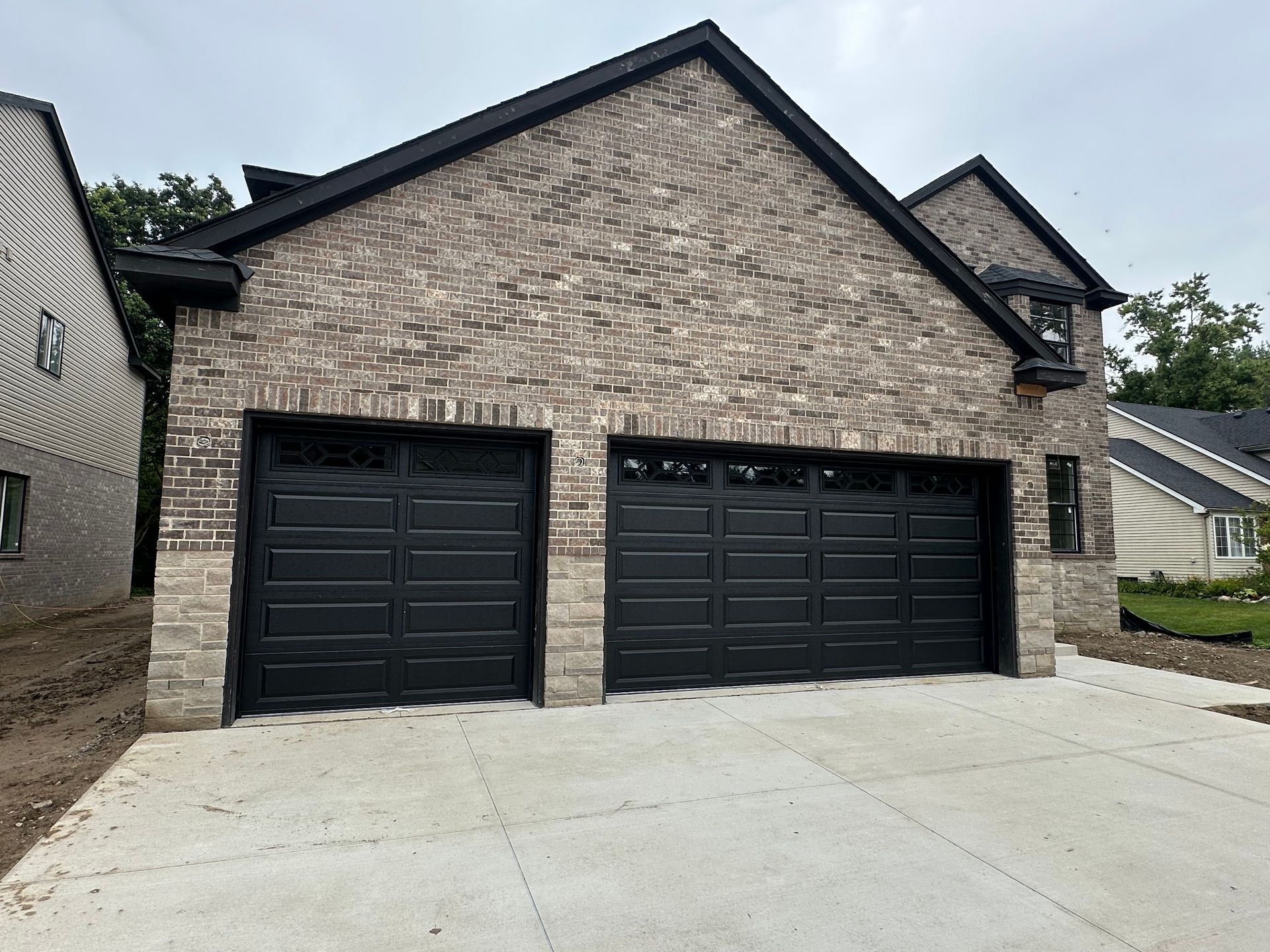 Two-car brick garage with black doors and concrete driveway.