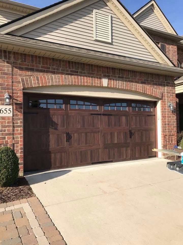 Brown garage door with windows, brick exterior, and concrete driveway.