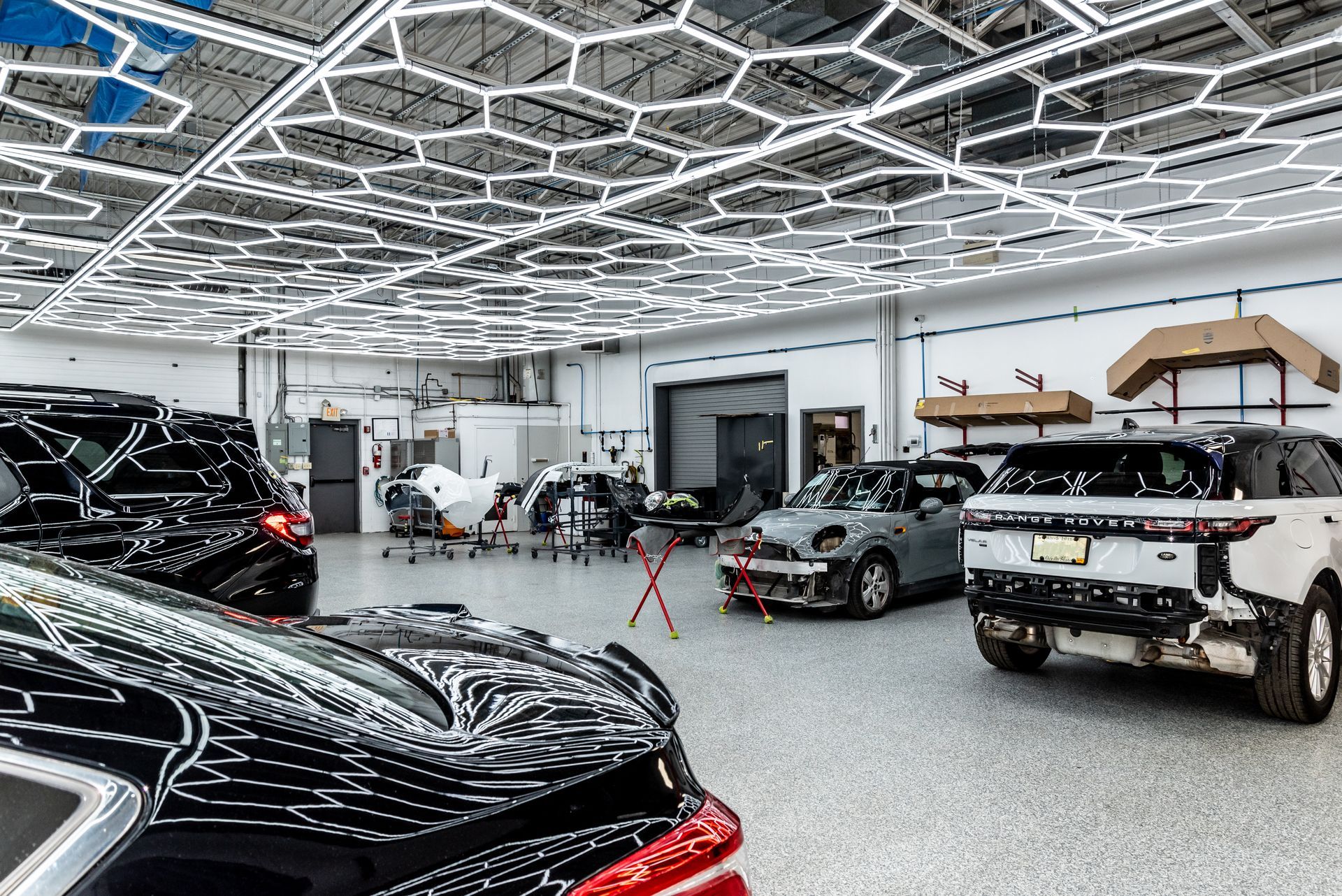 Cars inside a garage with hexagonal overhead lights; vehicle detailing or repair shop.