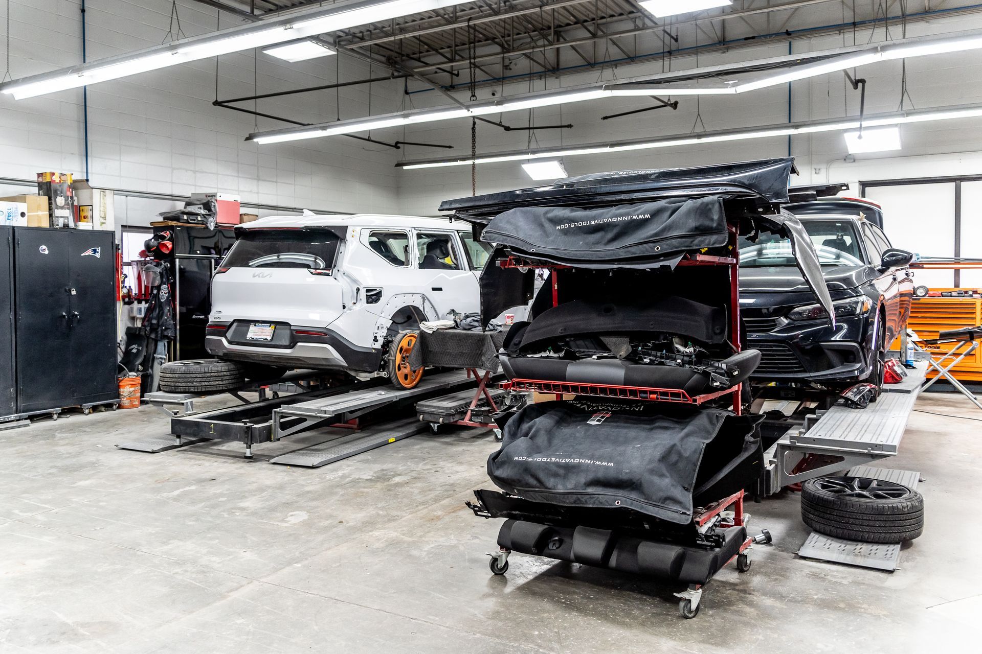 Cars on lifts in a repair shop; parts on a cart.