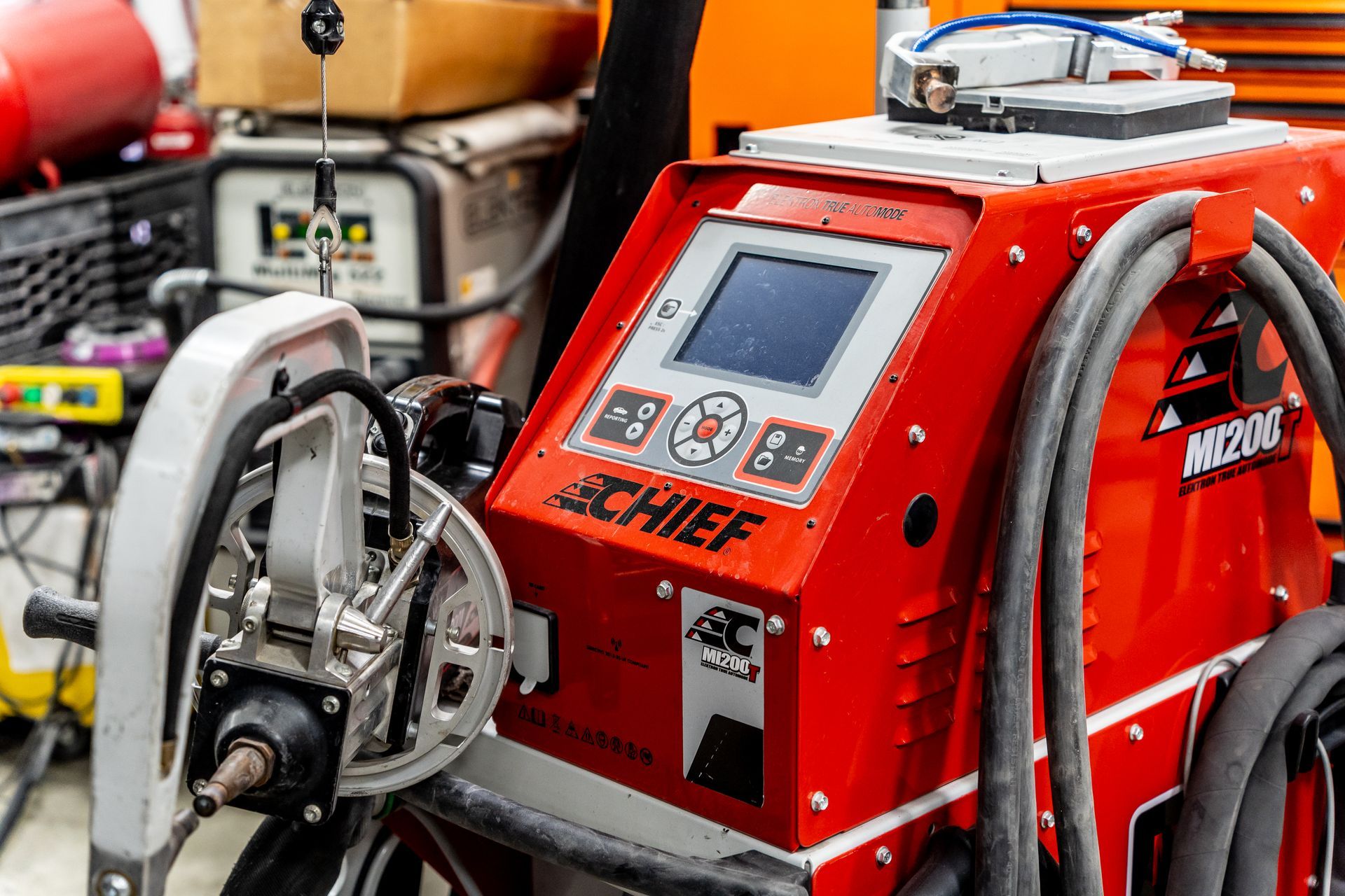 Red and white Chief MIG welding machine with a digital display and attached wire feeder in a workshop.