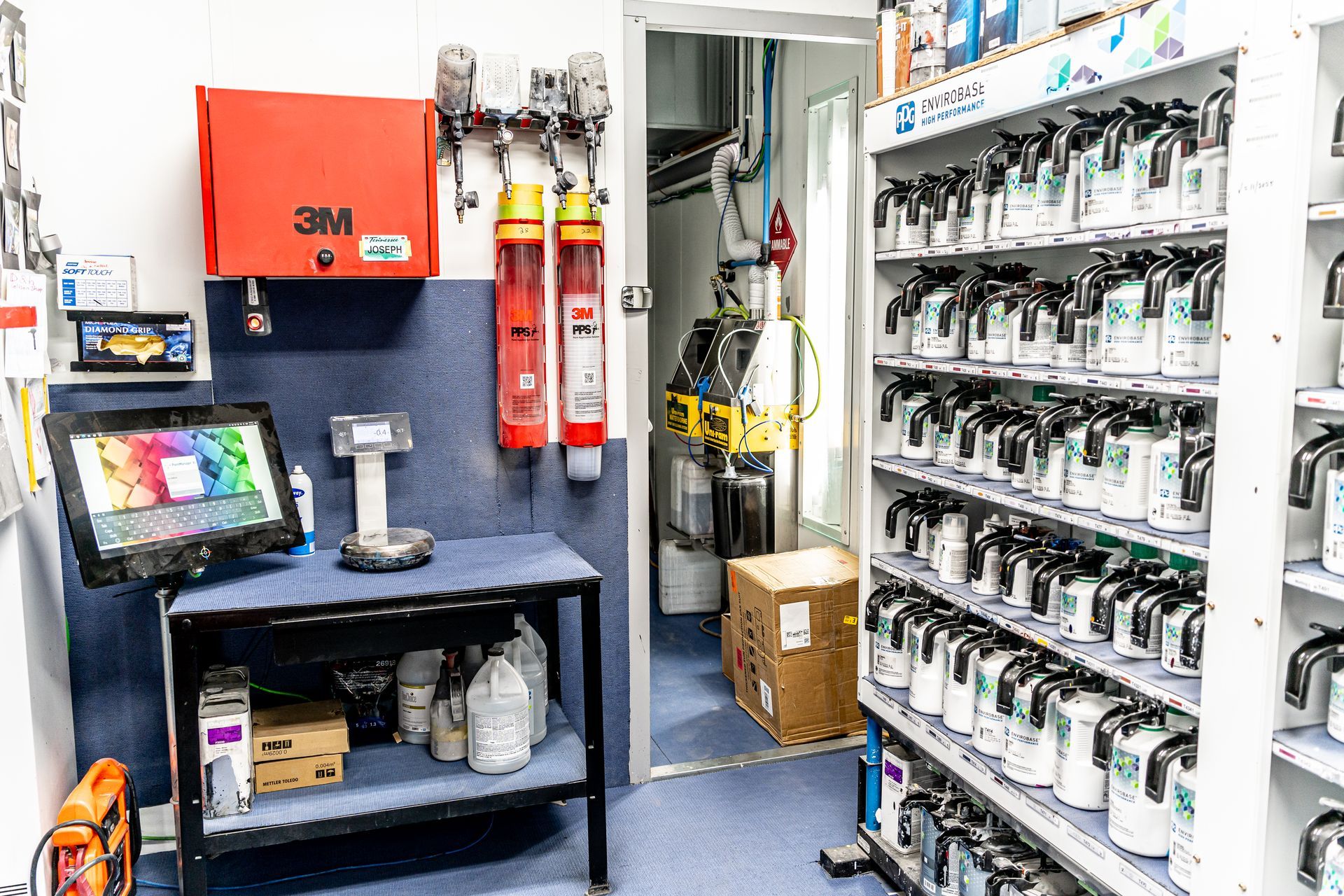 Paint mixing room with shelves of paint cans, computer, and safety equipment.