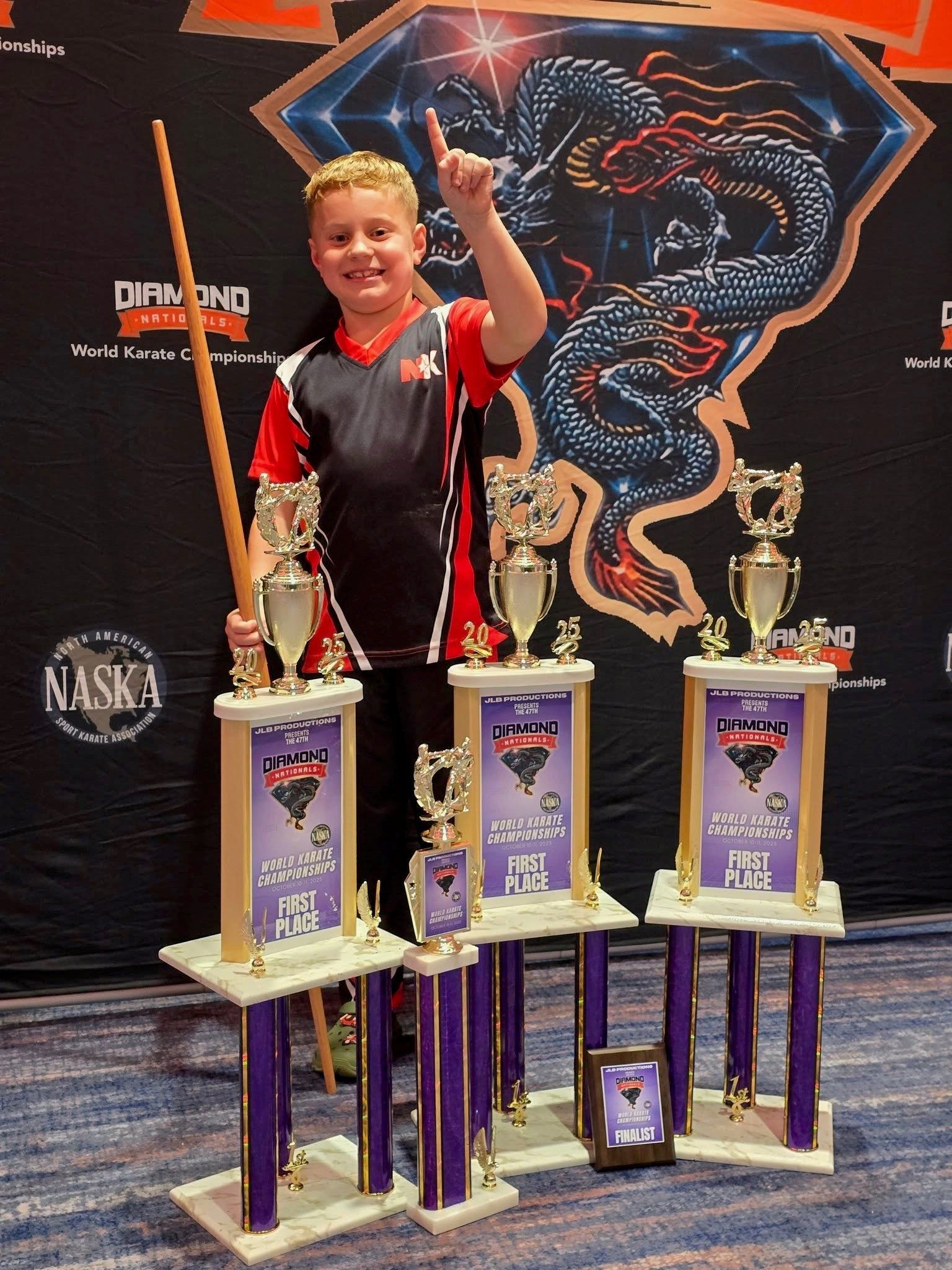 Young boy with trophies raises finger in victory