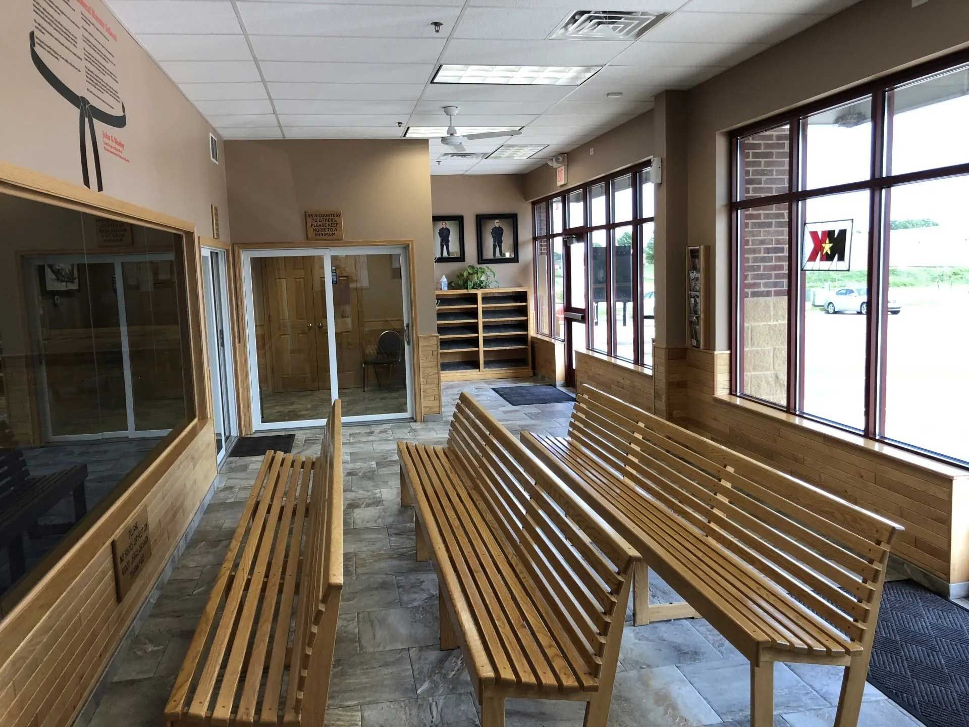 Waiting area with wooden benches, large windows, and a door.
