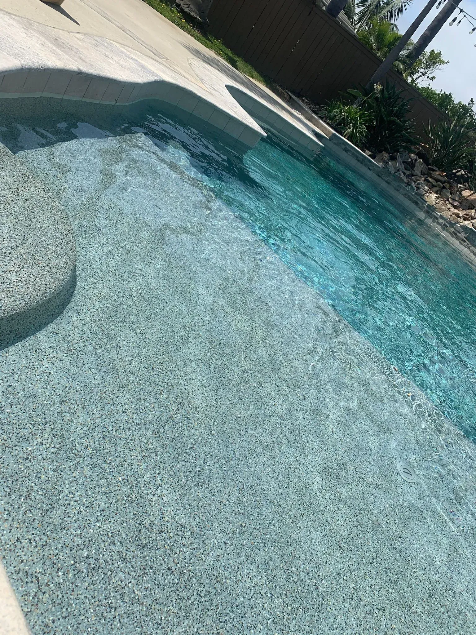 Pool with textured, light blue bottom and clear water. Circular steps.