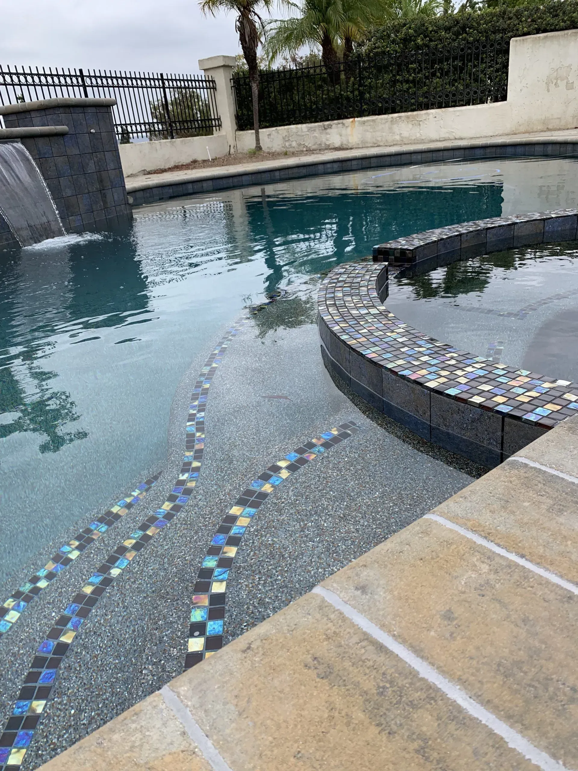 Pool and spa on a paved patio with a nice water feature.