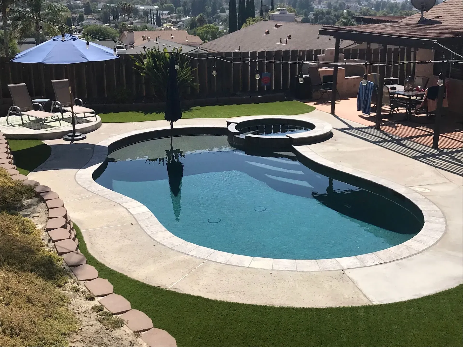 Backyard pool with spa, umbrella, lounge chairs, and artificial turf.