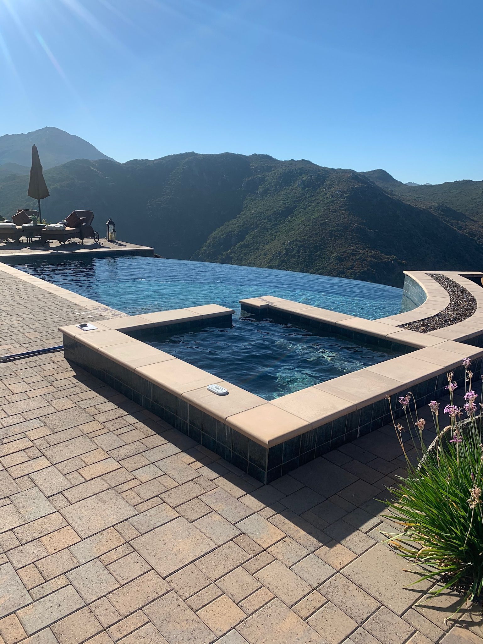 Swimming pool with a view of a mountain range under a clear blue sky.