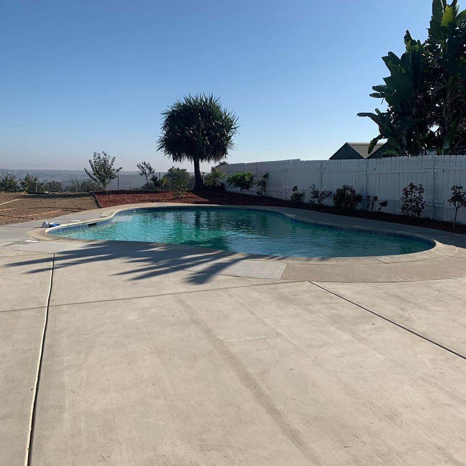 Swimming pool with concrete patio, overlooking a distant landscape under a clear blue sky.
