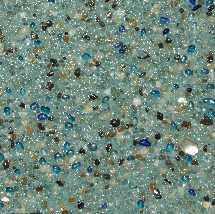 Close-up view of a pool interior with a mix of blue, brown, and clear glass beads embedded in a light blue surface.