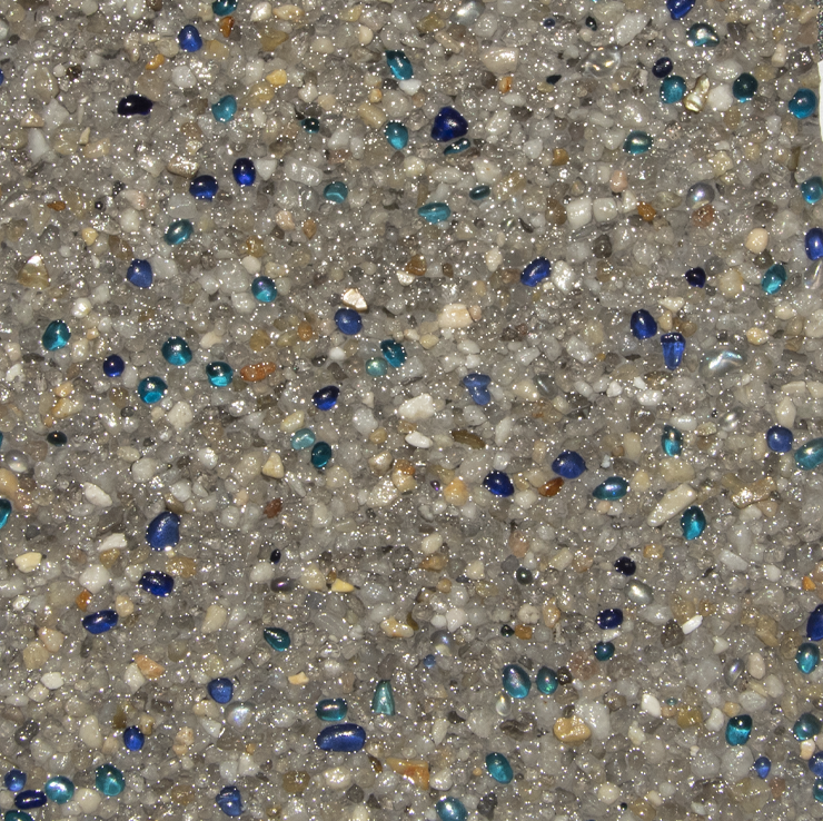 Textured surface of gray concrete with scattered blue and teal glass beads.
