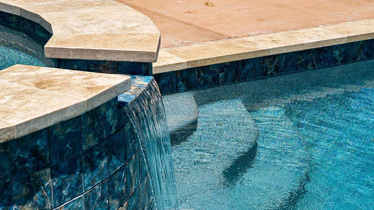 Pool with blue tile and waterfall feature, tan coping.
