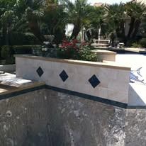 Pool with beige wall, blue diamond inlays, and plants.